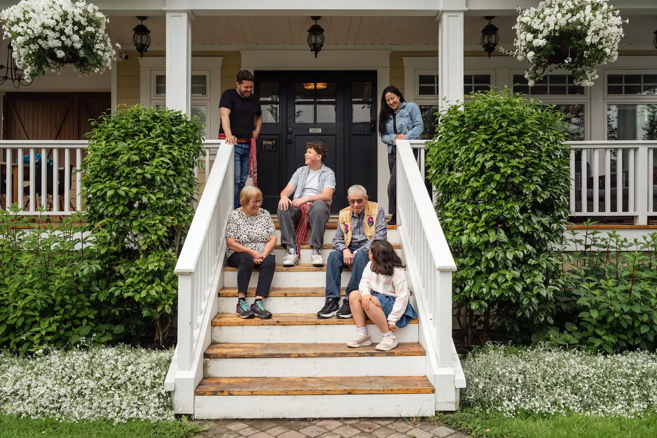 A family sitting together on the front steps of their porch