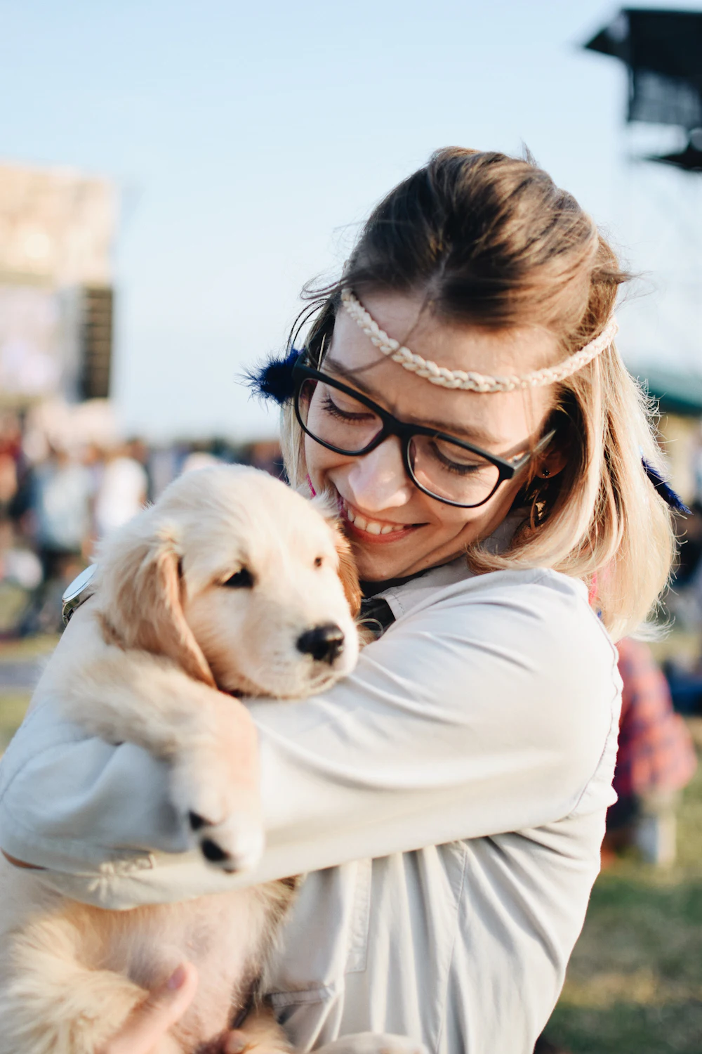A young woman holding a fluffy golden retriever puppy close