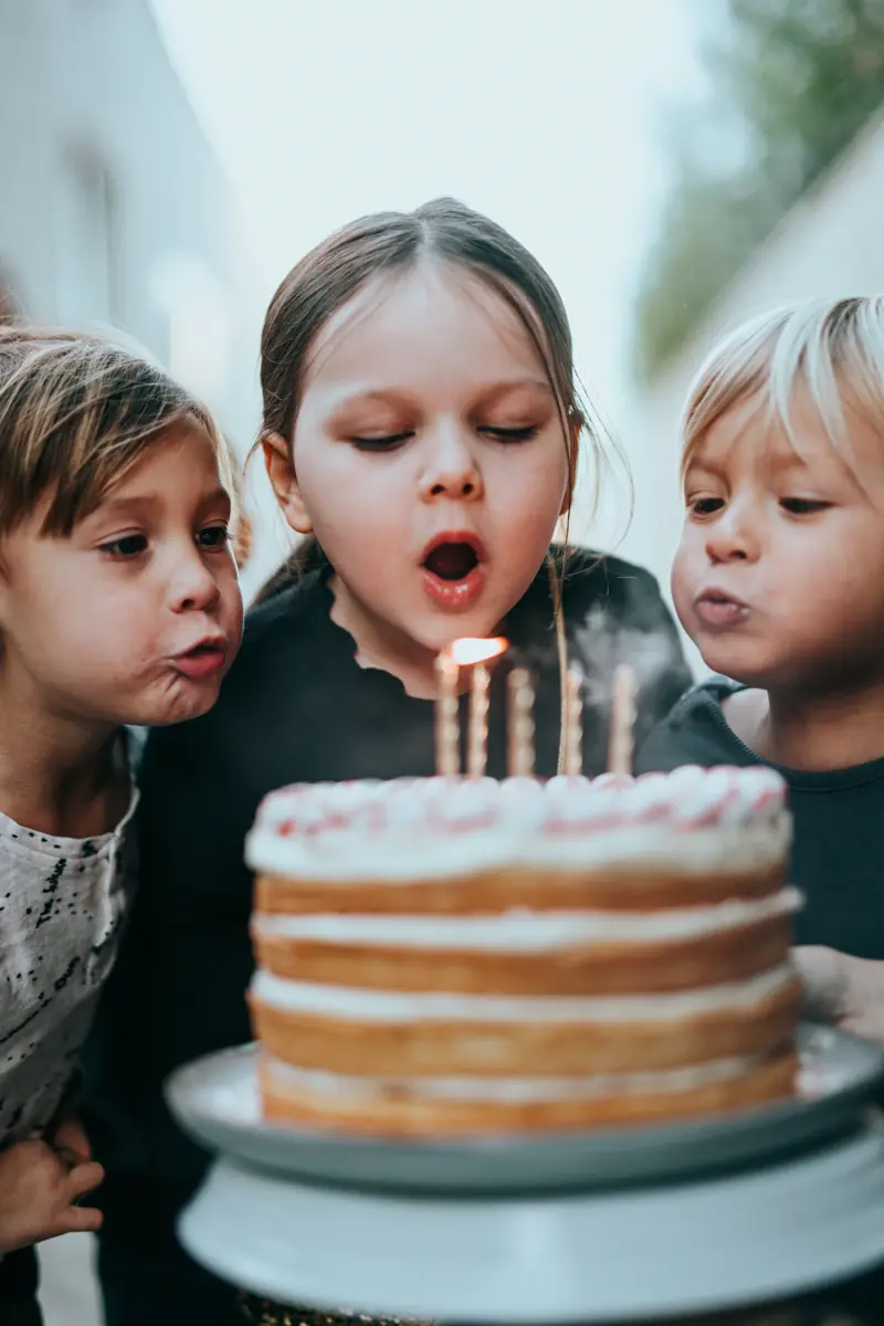 Kids blowing out candles on a birthday cake